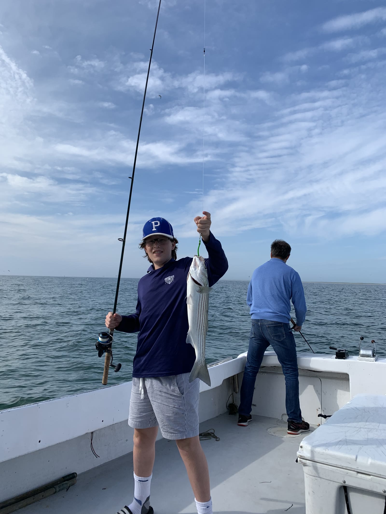 Theo holding a striped bass on a fishing boat