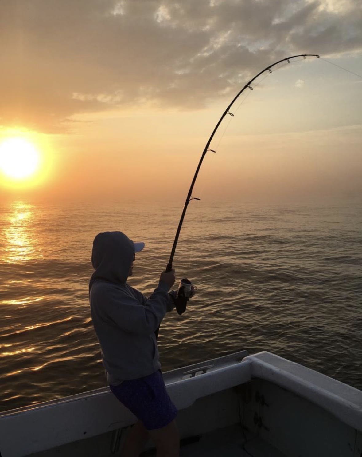Theo fishing at sunset from a boat